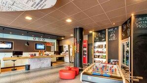 Un vestíbulo moderno con mostrador de recepción, mesa de futbolín y zona de bar.