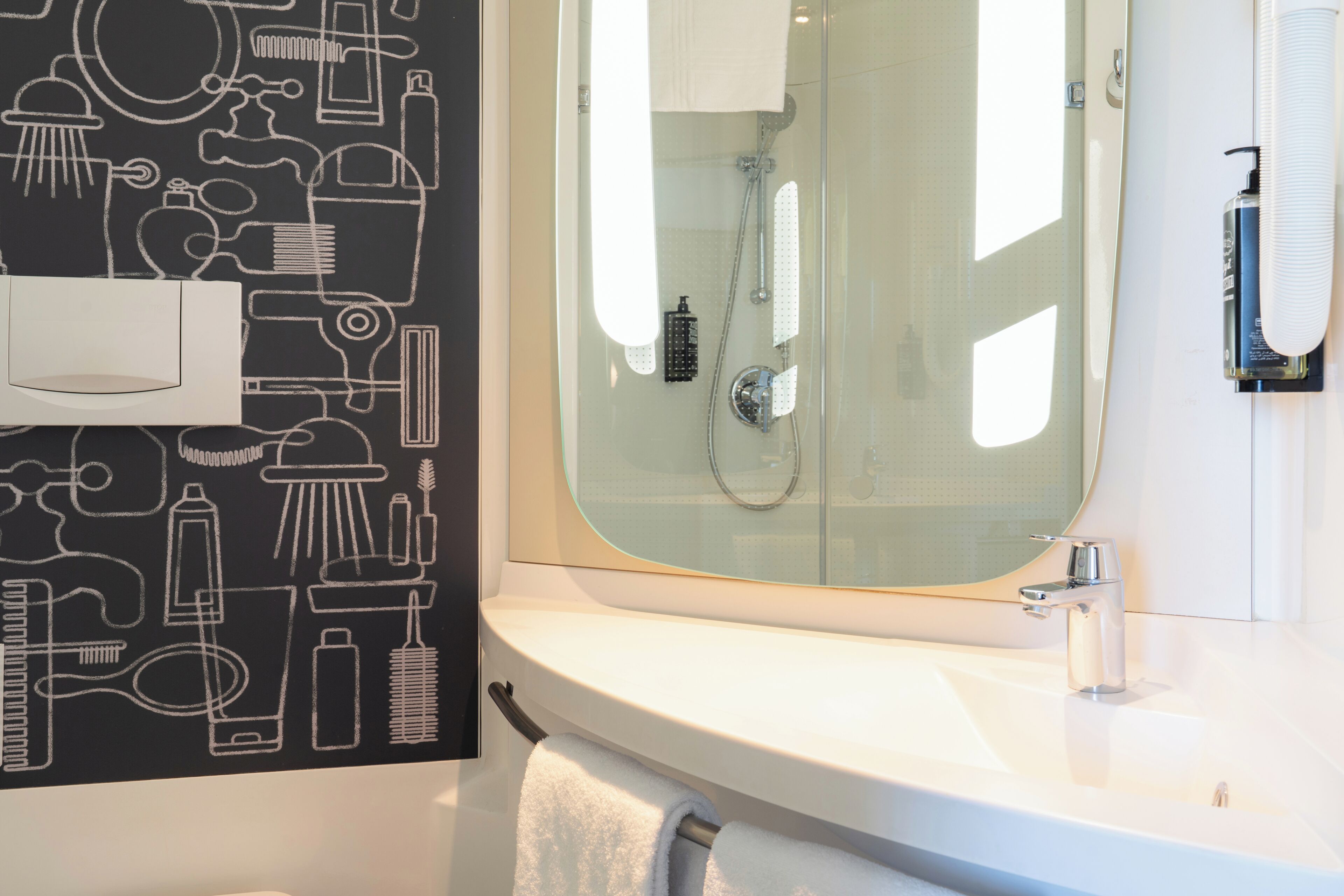 Une salle de bain avec une douche à parois de verre, un lavabo blanc et un porte-serviettes.