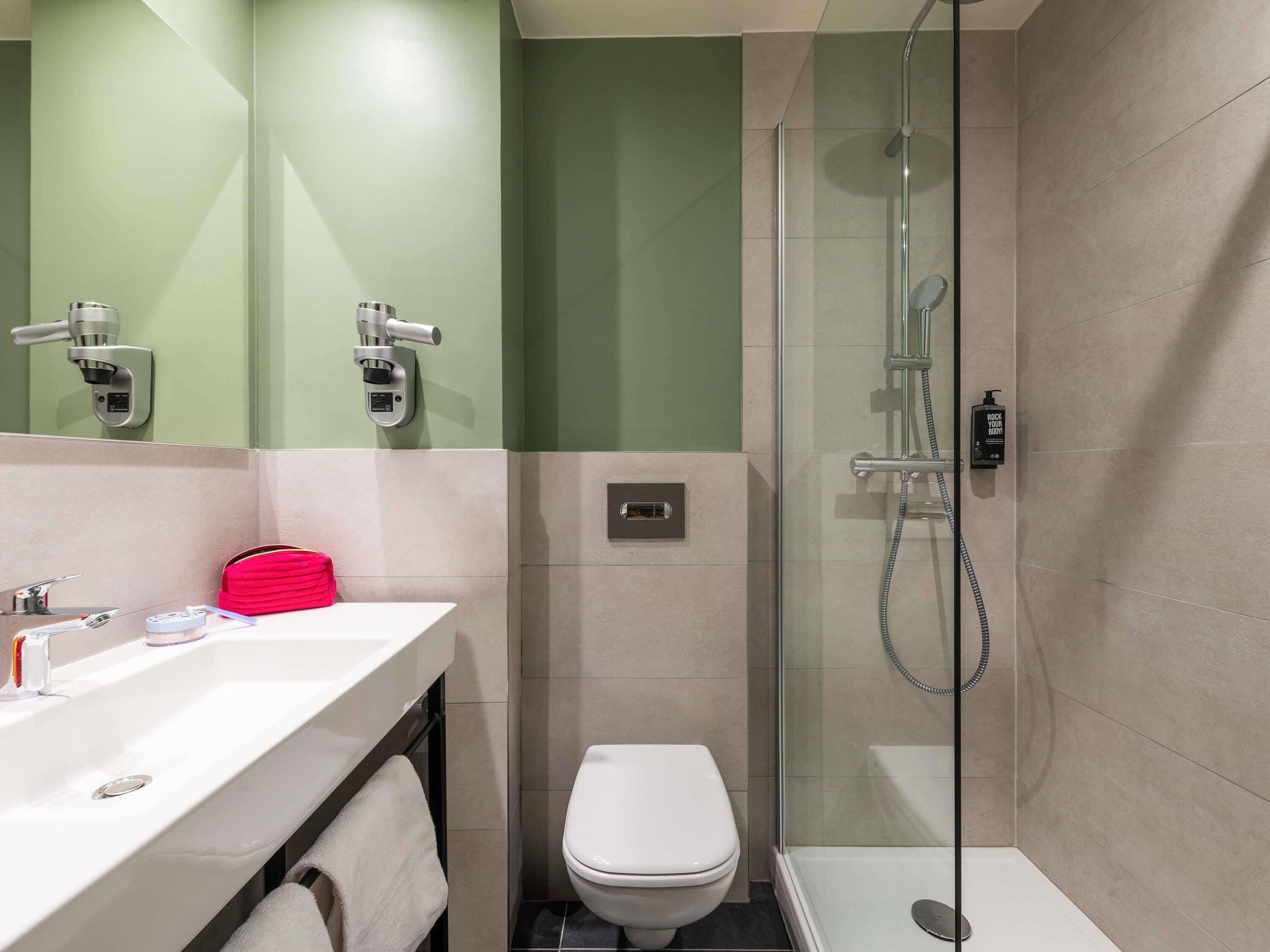 A modern bathroom with a shower, toilet, and sink.