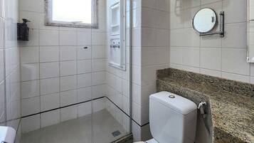 A bathroom with a shower, toilet, sink, and a window.