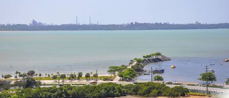A coastal view with boats, a beach, and a distant cityscape.