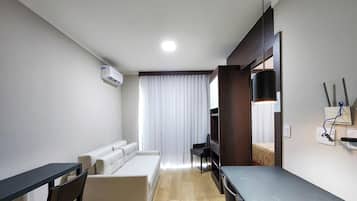 Una habitación de hotel moderna con sofá, mesa de comedor, televisor y aire acondicionado.