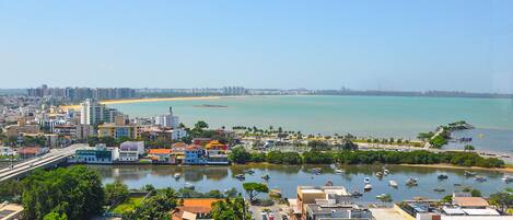 Un paisaje urbano costero con un puerto deportivo, edificios y una playa al fondo.