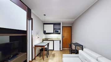 A compact living space with a kitchenette, a dining area, a sofa, and a TV.