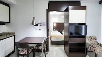 Een compacte hotelkamer met kitchenette, een bed, een televisie en een zithoekje.