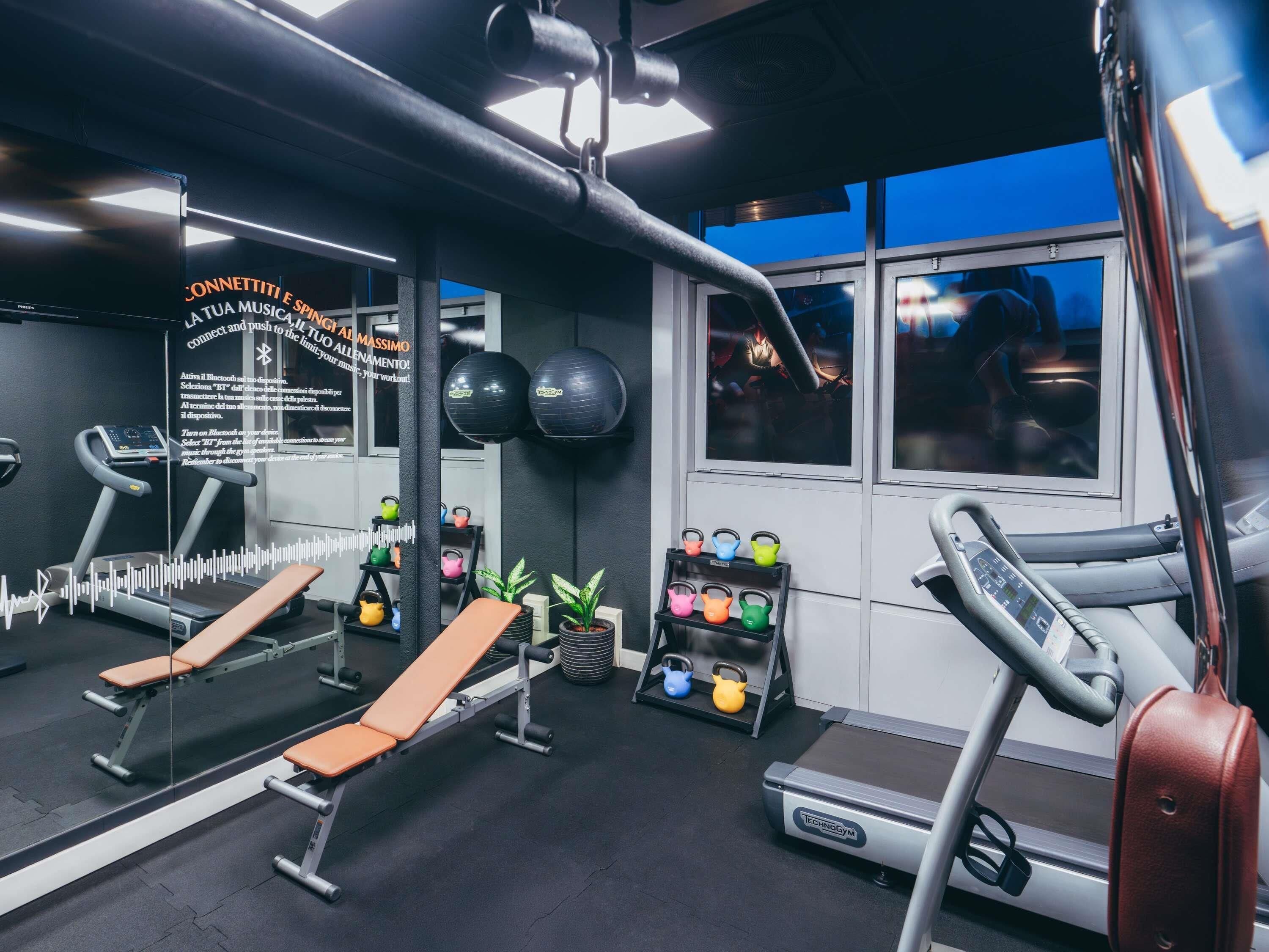 A gym with exercise equipment, a bench, kettlebells, and a mirror.