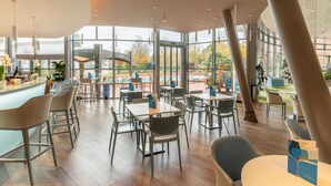 Un espacio interior amplio con ventanas grandes, muebles modernos y vistas a un parque infantil al aire libre.