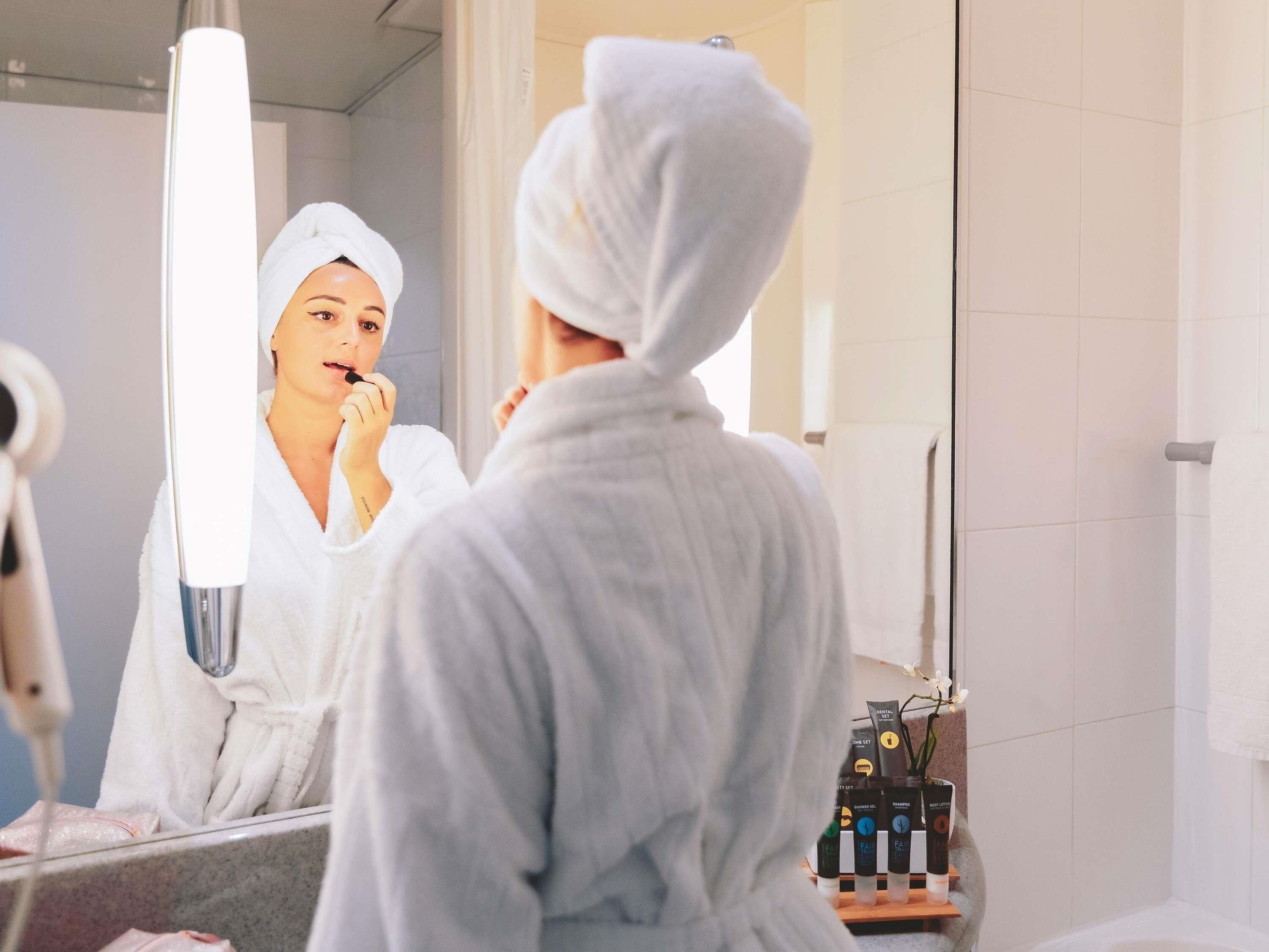 Un bagno con specchio, portasciugamani e ripiano con articoli da toilette.