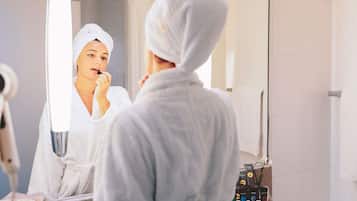 Un bagno con specchio, portasciugamani e ripiano con articoli da toilette.