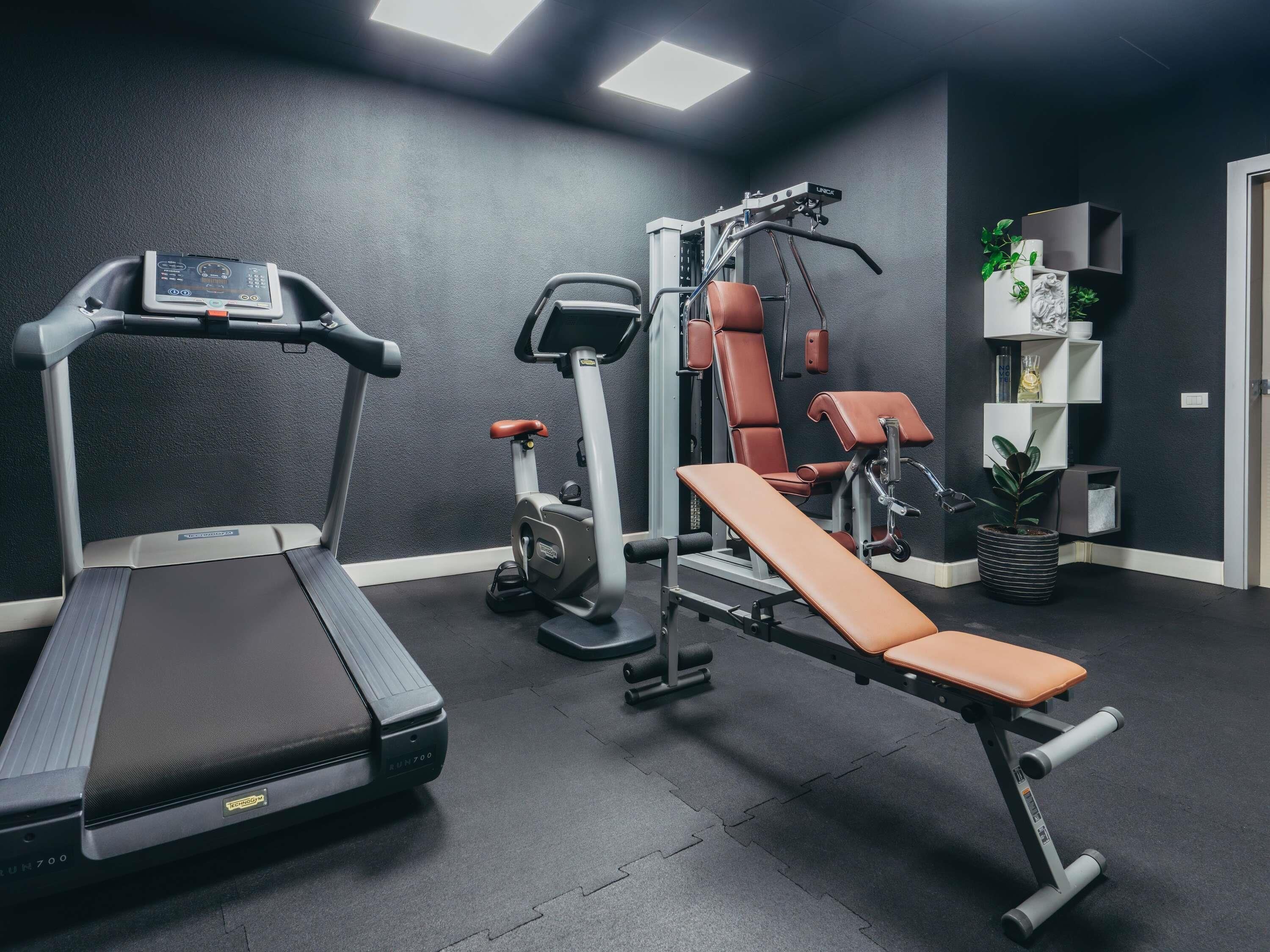 A gym with a treadmill, elliptical, bench press, and weight machines.