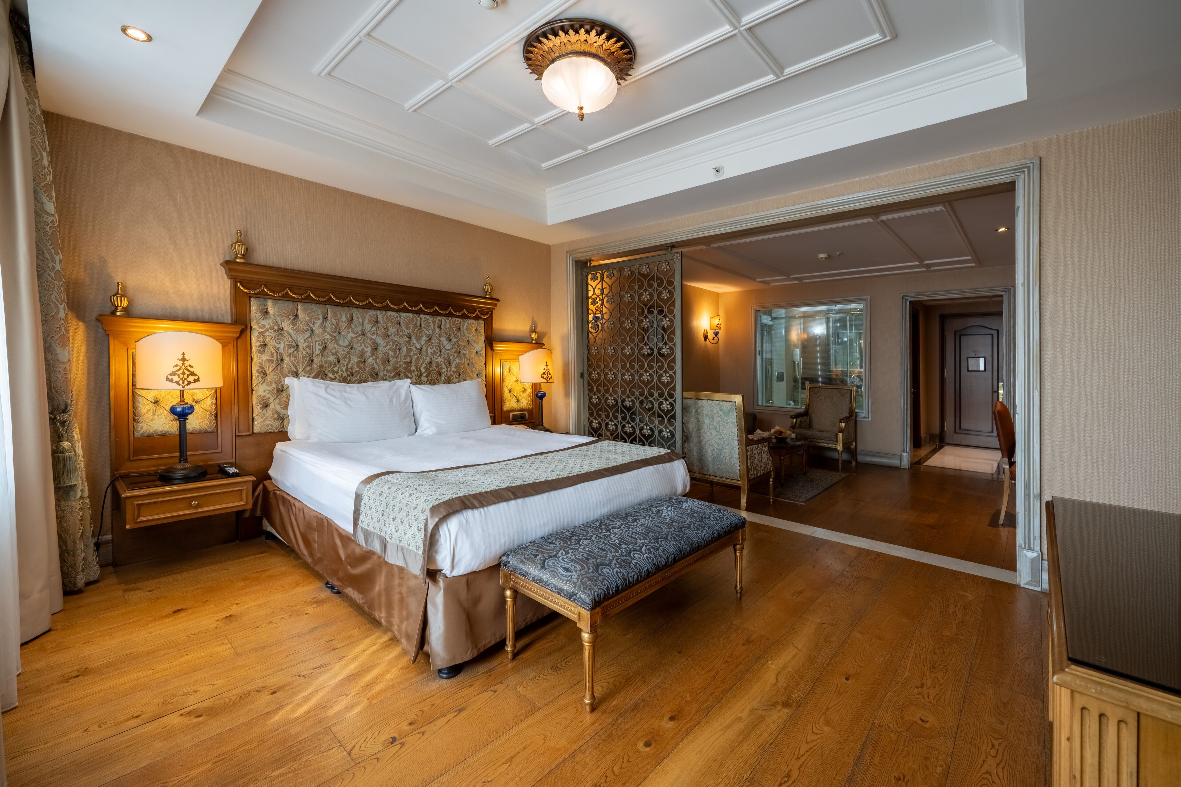 Une chambre spacieuse avec un grand lit, un plancher en bois et un banc.