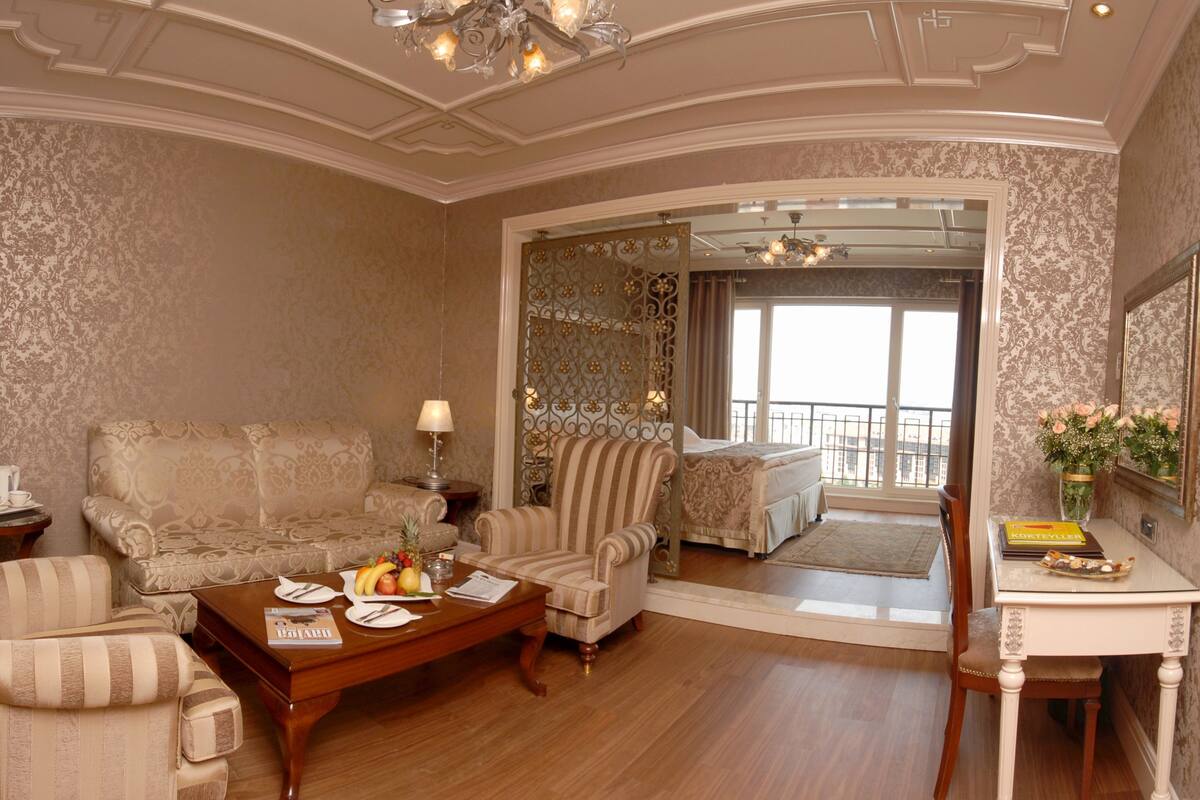 A spacious living room with a sofa, armchairs, a coffee table with fruit, and a dining area with a table and chairs.
