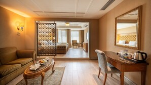 Ett hotellrum med en soffa, ett matbord, en kaffebryggare och en spegel.