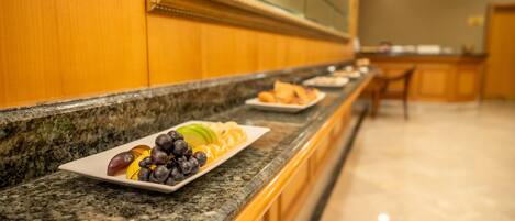 Un bufé de hotel con encimera de mármol, un plato de frutas y un espejo sobre la encimera.
