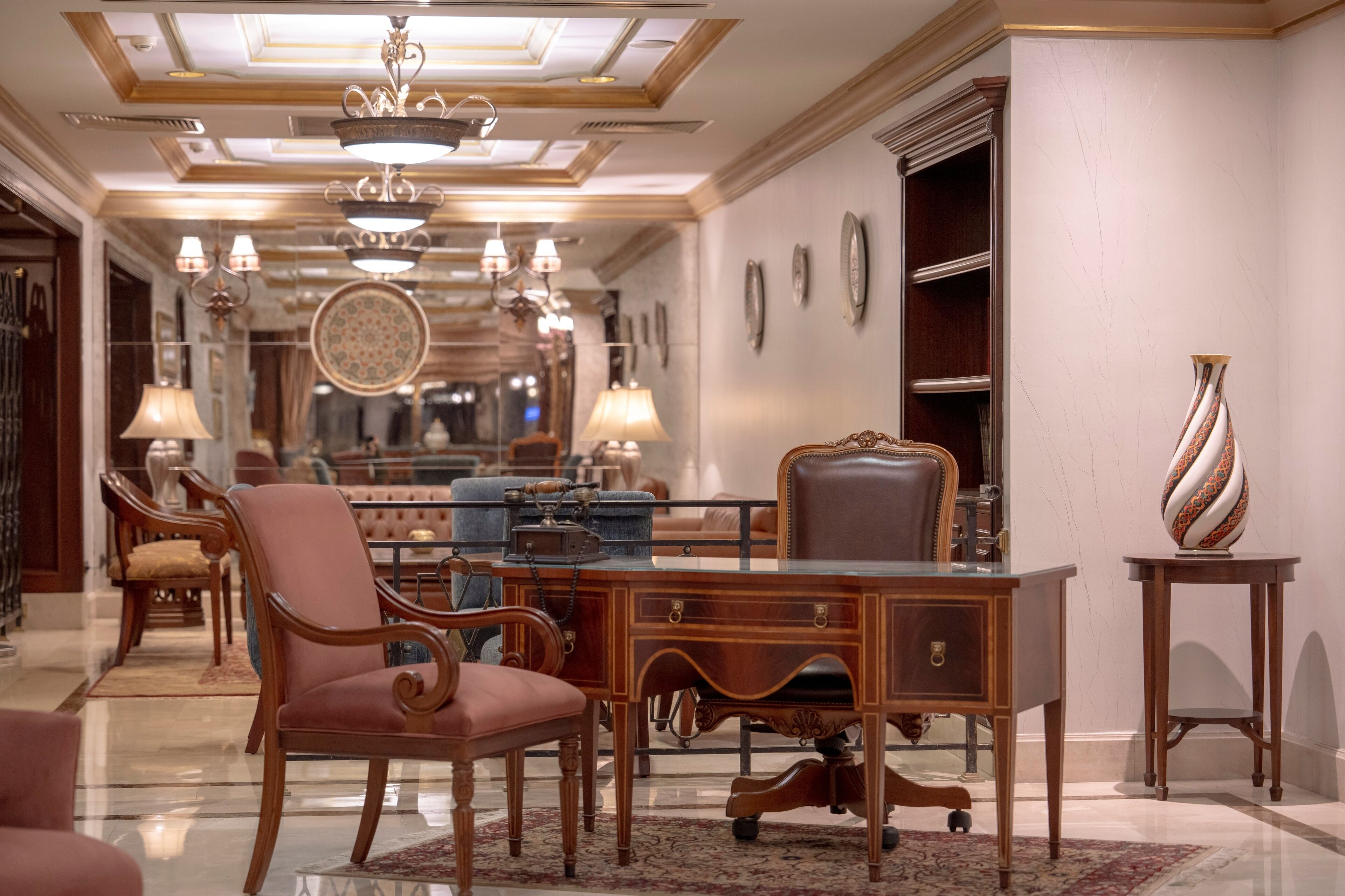 A spacious hallway with elegant furniture, including a desk, chairs, and a sofa.