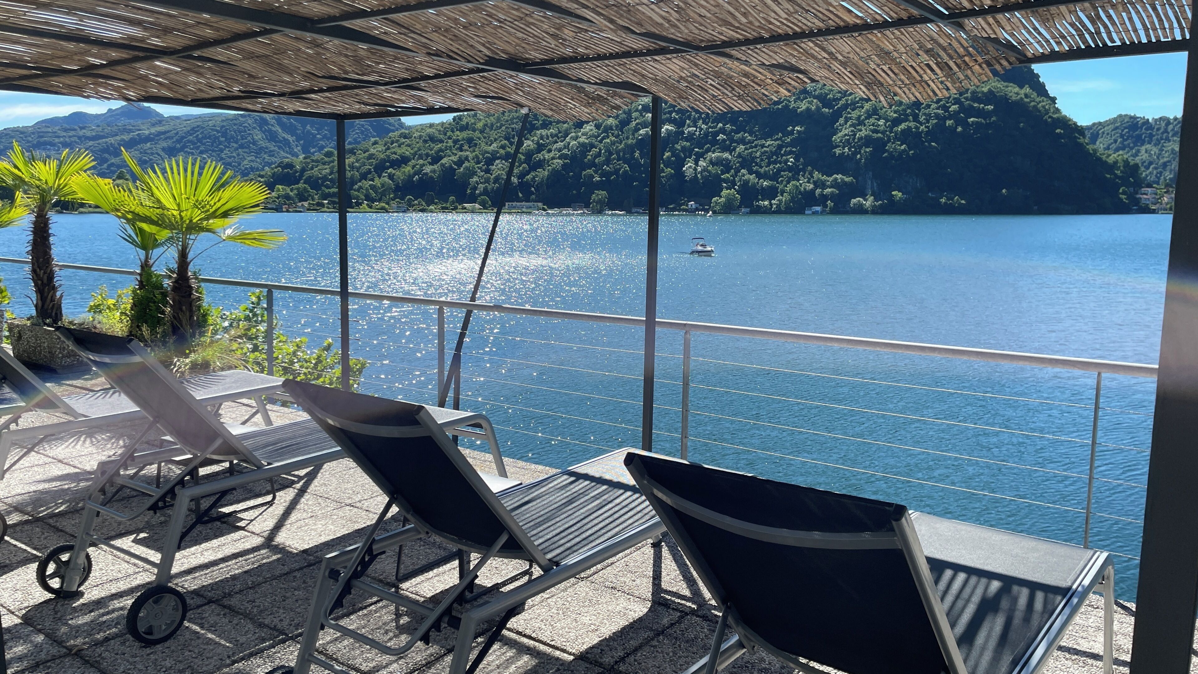Una terraza con sillones de descanso y vistas a un lago y colinas boscosas.