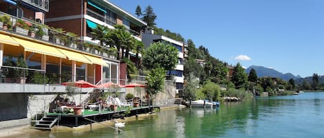 Hotel a orillas del río con terraza al aire libre y un cisne en el agua.