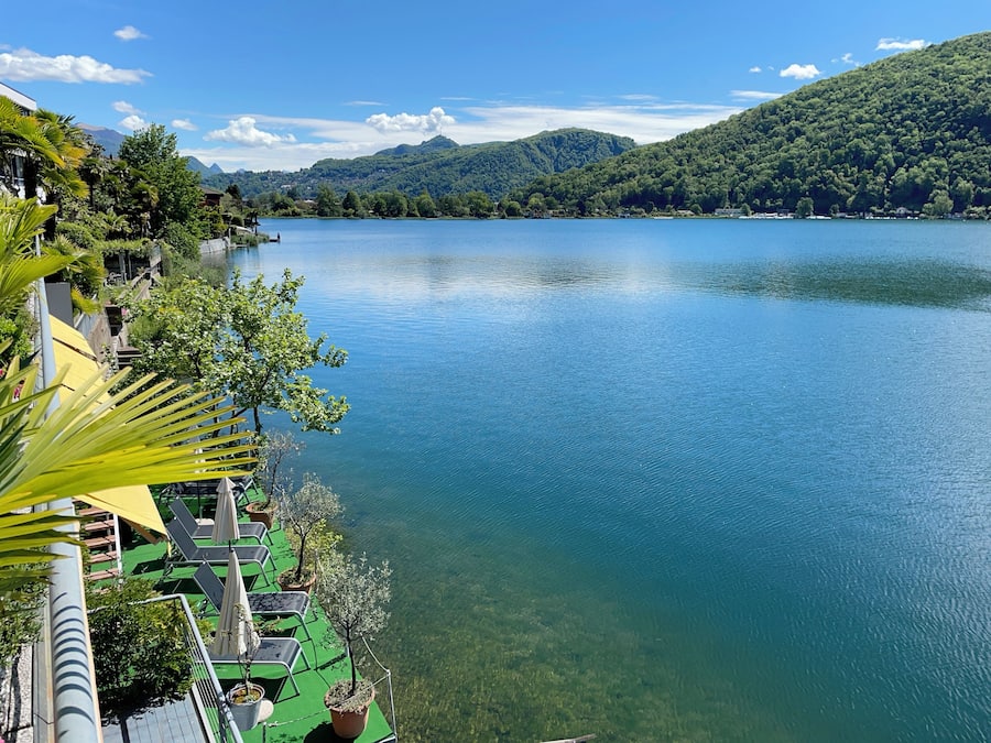 Vista al lago con un muelle, plantas en macetas y cielo despejado.