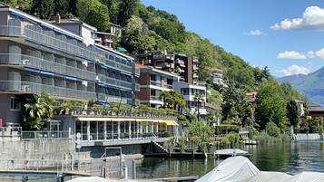 A waterfront hotel with balconies, a covered walkway, and a view of the lake and mountains.