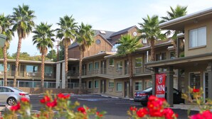 A hotel with multiple floors, palm trees, and a parking lot. - The Inn at St George (St. George)