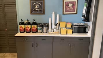 Una estación de café con varios dispensadores, un microondas y una máquina de café.