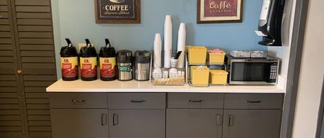 Una estación de café con varios dispensadores, un microondas y una máquina de café.