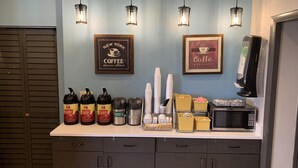 A coffee station with dispensers, cups, and a microwave. - Days Inn by Wyndham Louisville Airport Fair and Expo Center (Louisville)