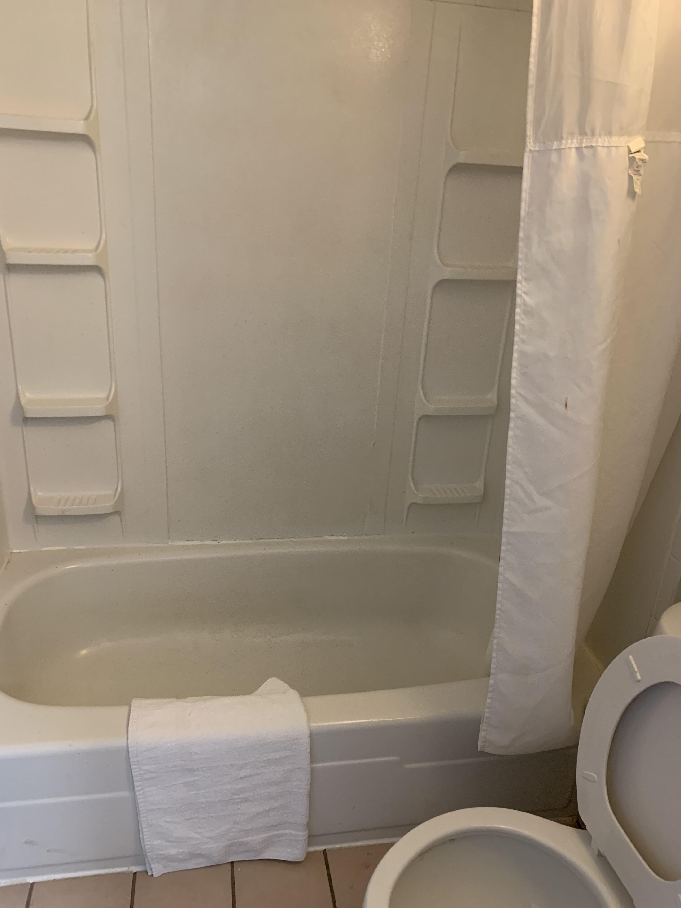 A bathroom with a bathtub, toilet, and a shower curtain.