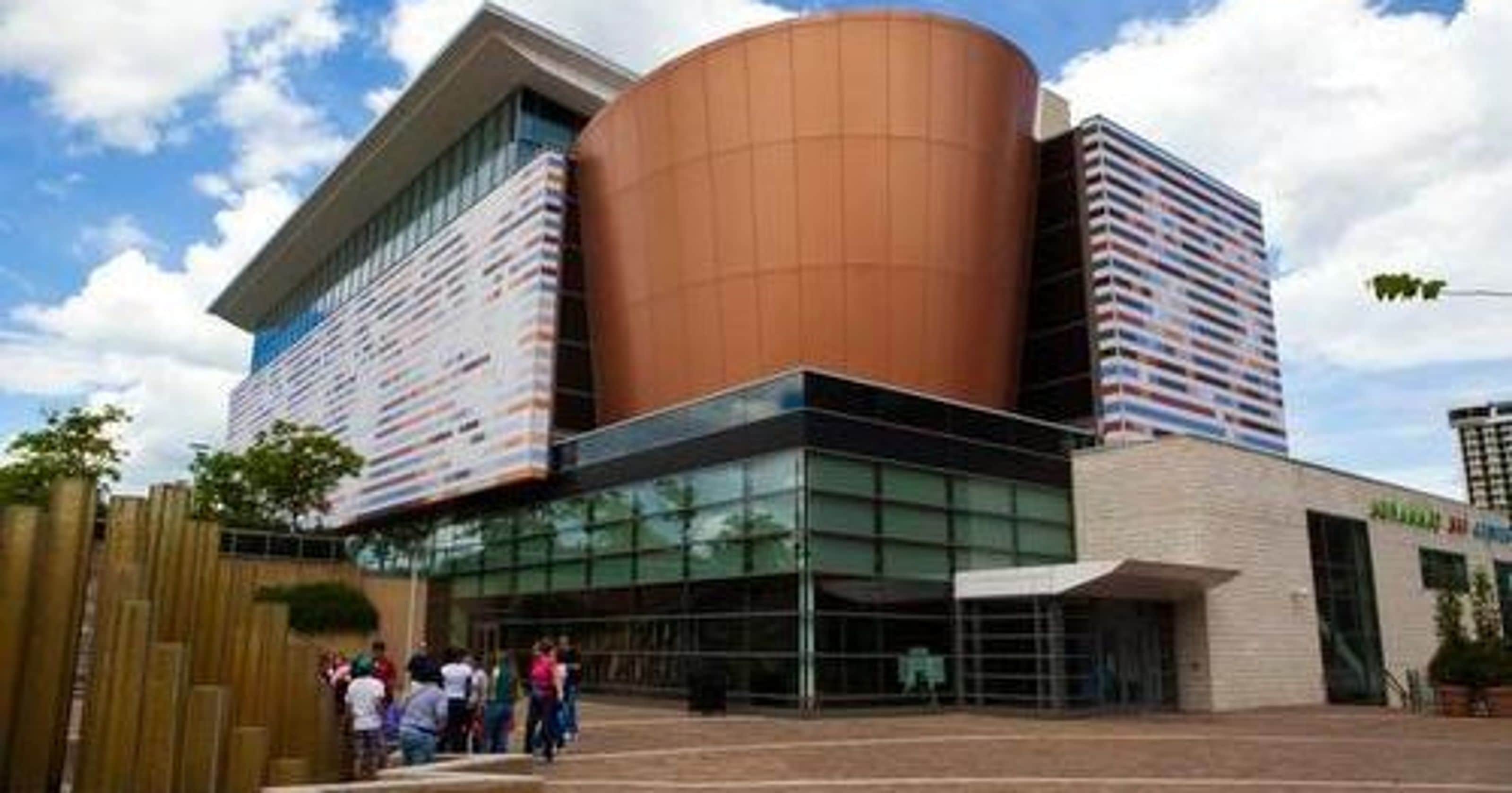 Un edificio moderno con una gran estructura cilíndrica y fachada de vidrio.