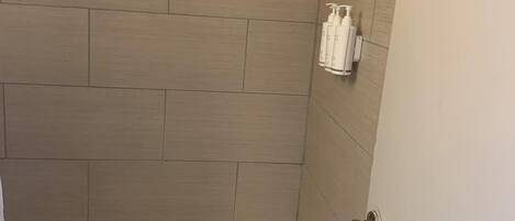 Une salle de bain avec une baignoire, des murs carrelés de couleur beige et une serviette accrochée sur le côté.