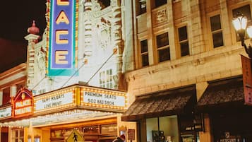 Um teatro com uma marquise exibindo "PALACE THEATRE" e um letreiro anunciando "PREMIUM SEATS" com um número de telefone.