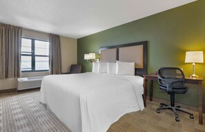 A hotel room with a large bed, a desk with a chair, a lamp, and a window with curtains. - Extended Stay America Suites Washington DC Springfield (Springfield)