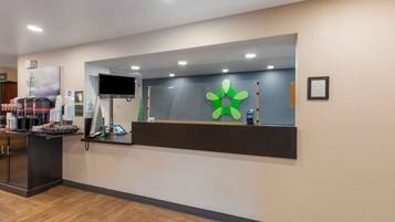 Uma mesa de recepção com uma televisão de tela plana, um logotipo verde e um caixa registradora.