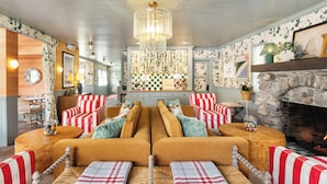 A cozy living room with a central sofa set, a stone fireplace, and a chandelier.