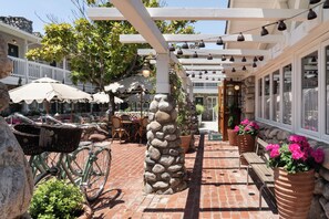 A patio area with a stone pillar, wicker chairs, a bicycle, and potted plants.