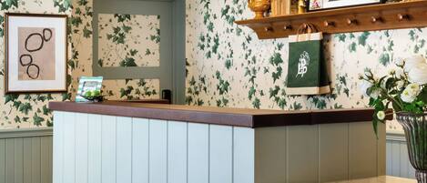 A reception area with a counter, a mirror, and a shelf with decorative items.