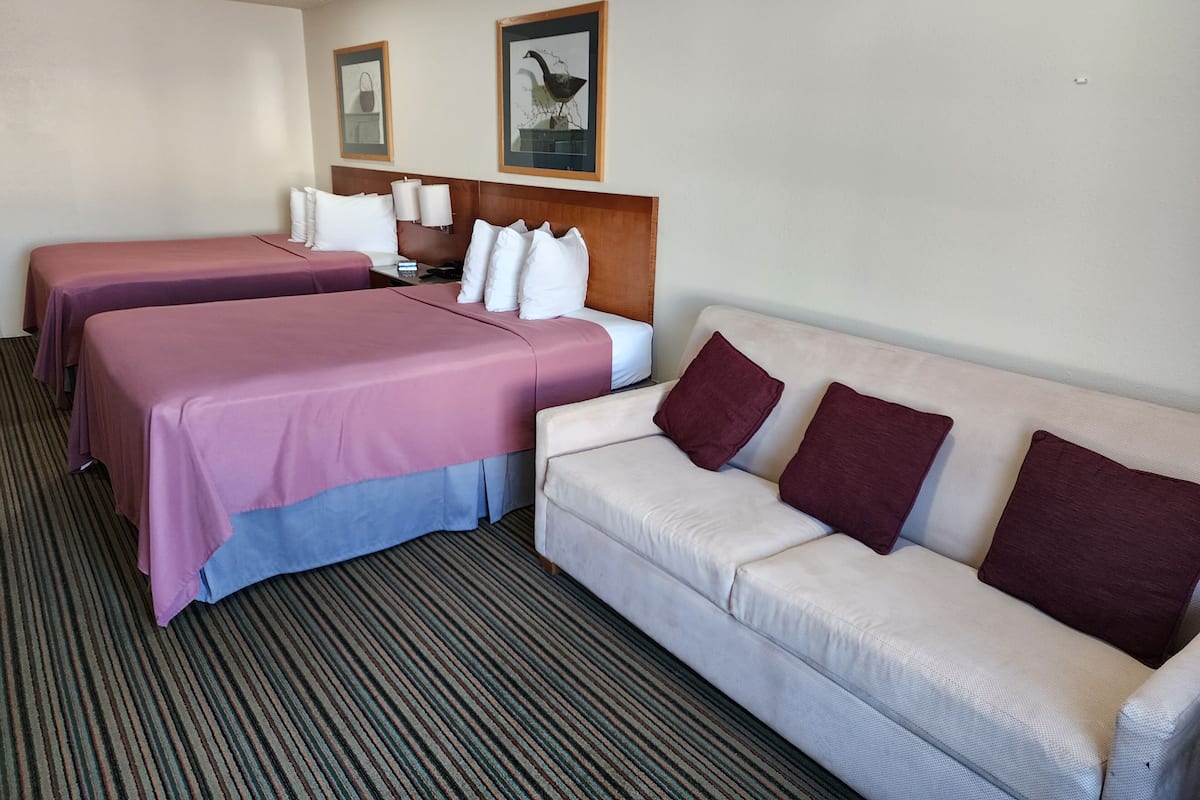 A hotel room with two single beds and a sofa.