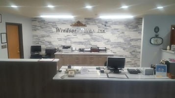 A reception desk with a nameplate, a clock, and a computer monitor.