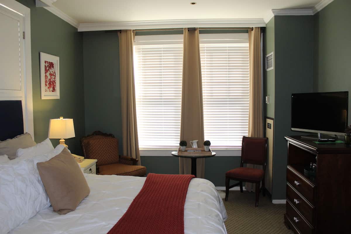 Une chambre d’hôtel avec un lit, une télévision, un bureau et une chaise.
