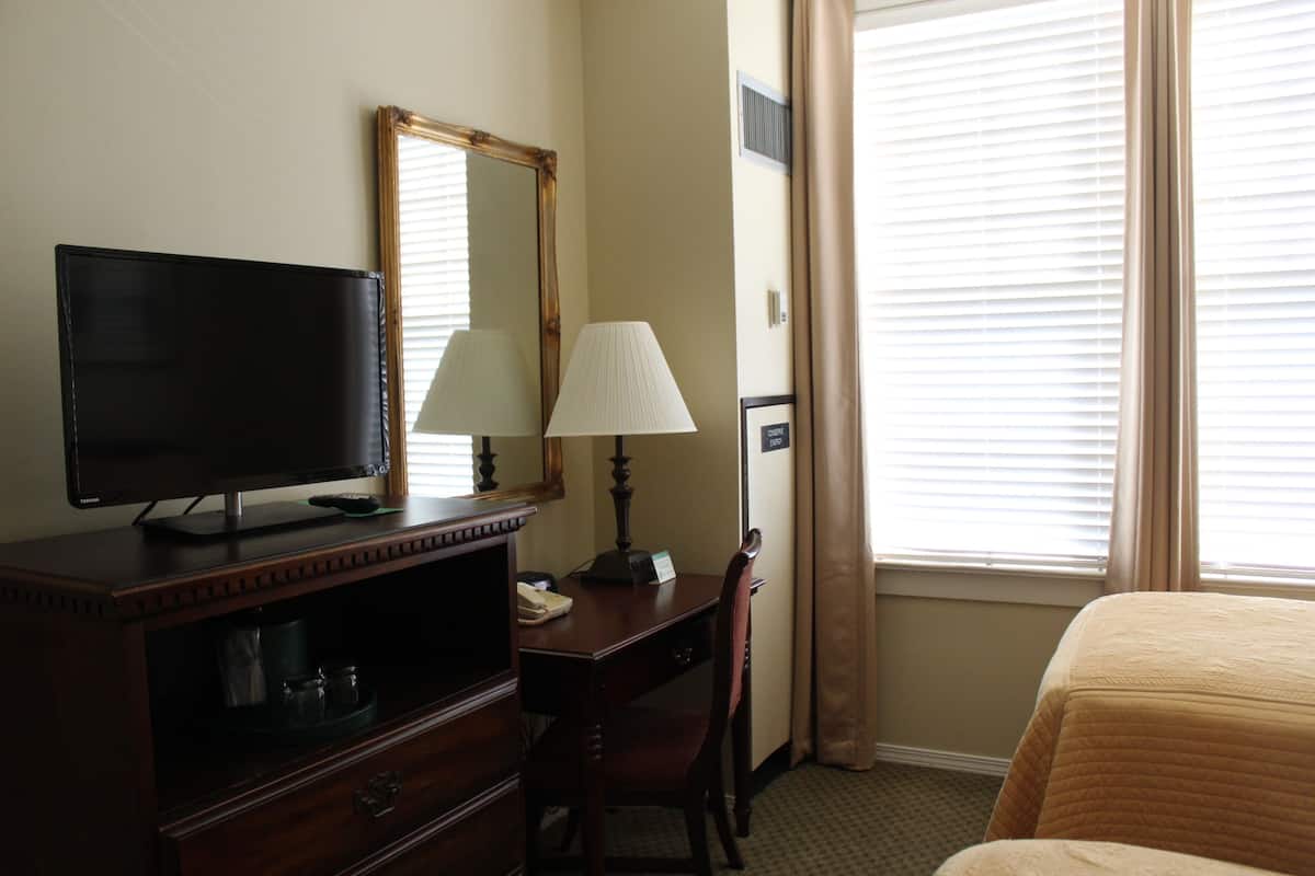 Une chambre d’hôtel équipée d’un bureau, d’une chaise, d’une télévision, d’une lampe et d’un lit.