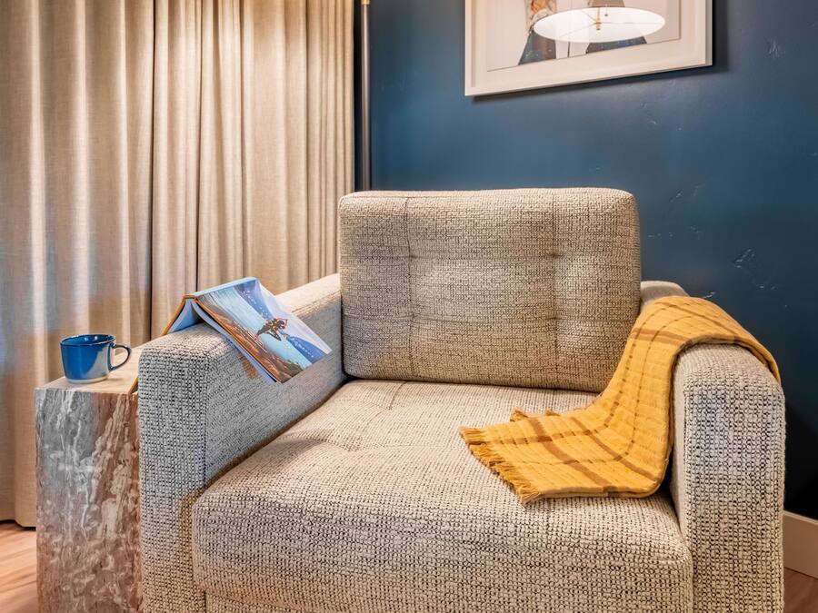 A cozy living room with a sofa, a side table, a lamp, and a framed picture on the wall.