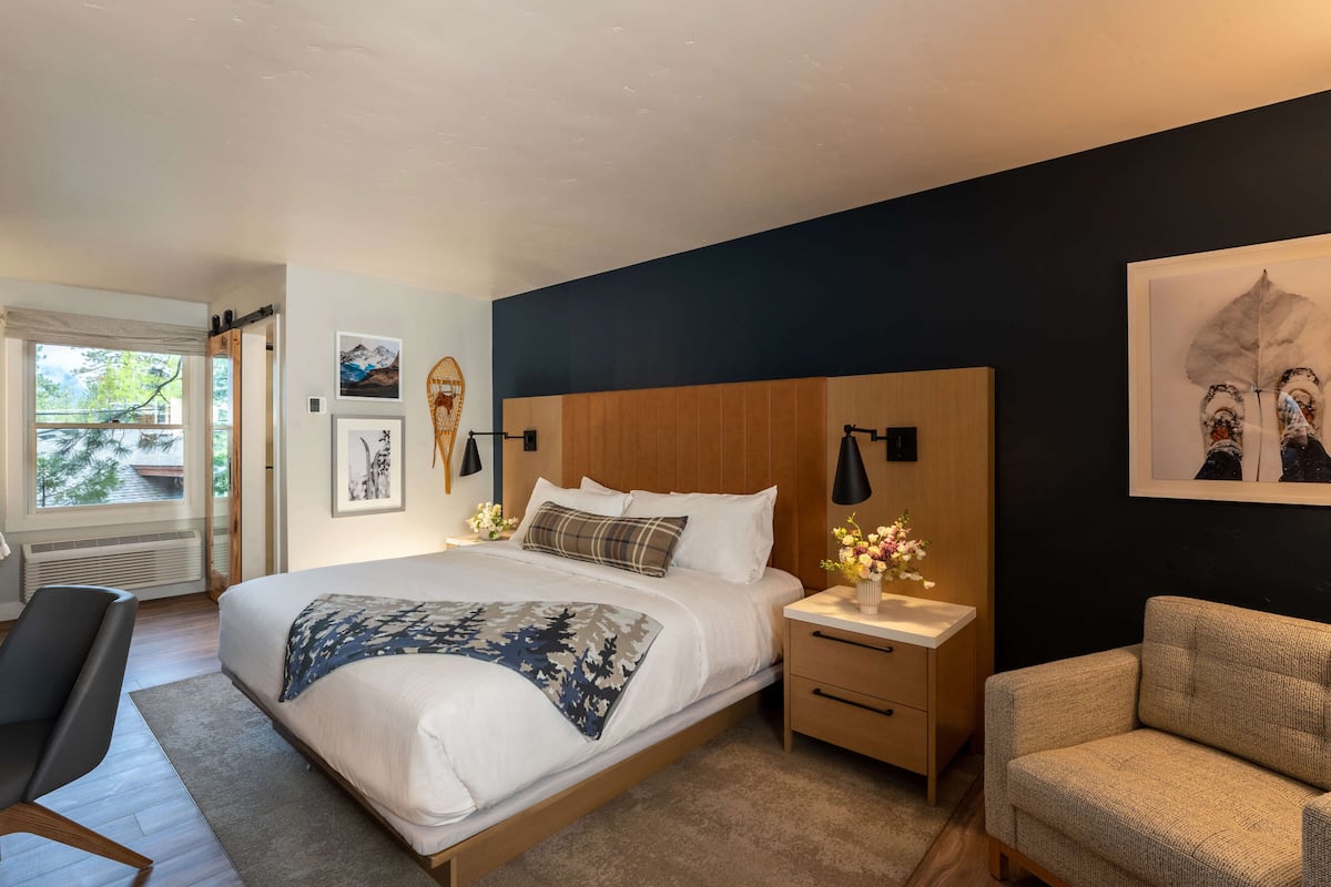 A modern bedroom with a large bed, bedside tables, a chair, and artwork on the walls.