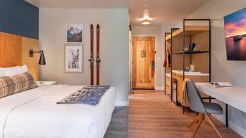 Una habitación de hotel moderna con cama, escritorio y vista al pasillo.