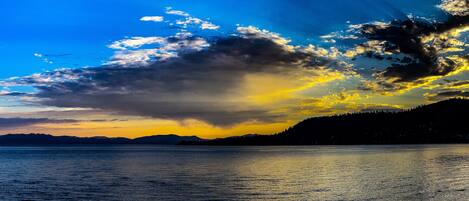 A calm lake with a mountain range in the background and a sunset sky.
