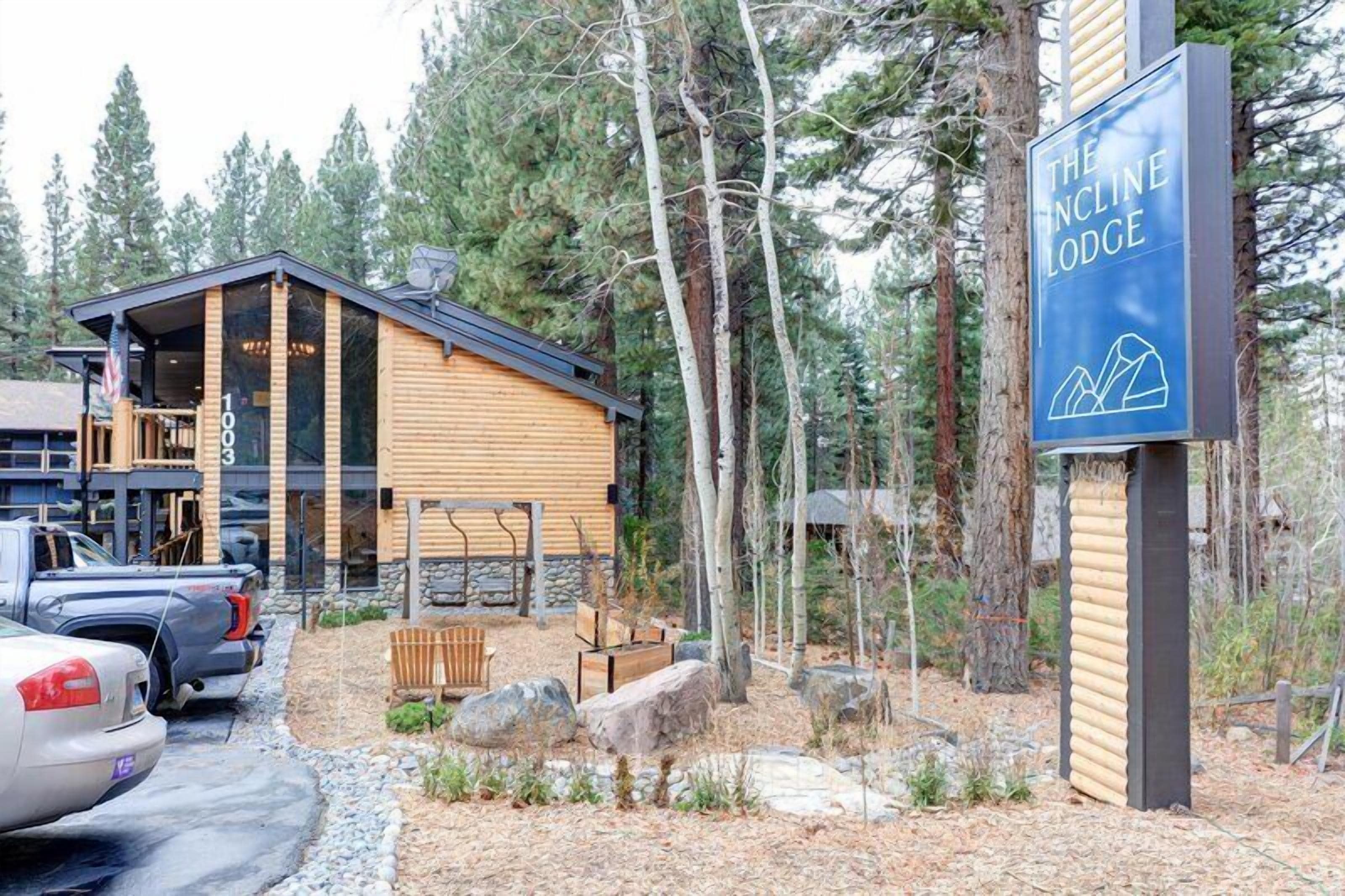 A lodge with a wooden exterior, a signboard, and a parking area.