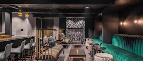 Een moderne lounge met zitplaatsen, een bar en een open haard.