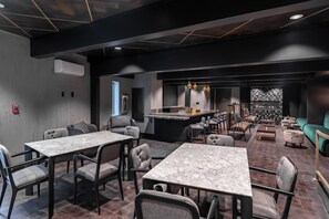A modern restaurant with marble tables and cushioned chairs, a bar area, and a green sofa.