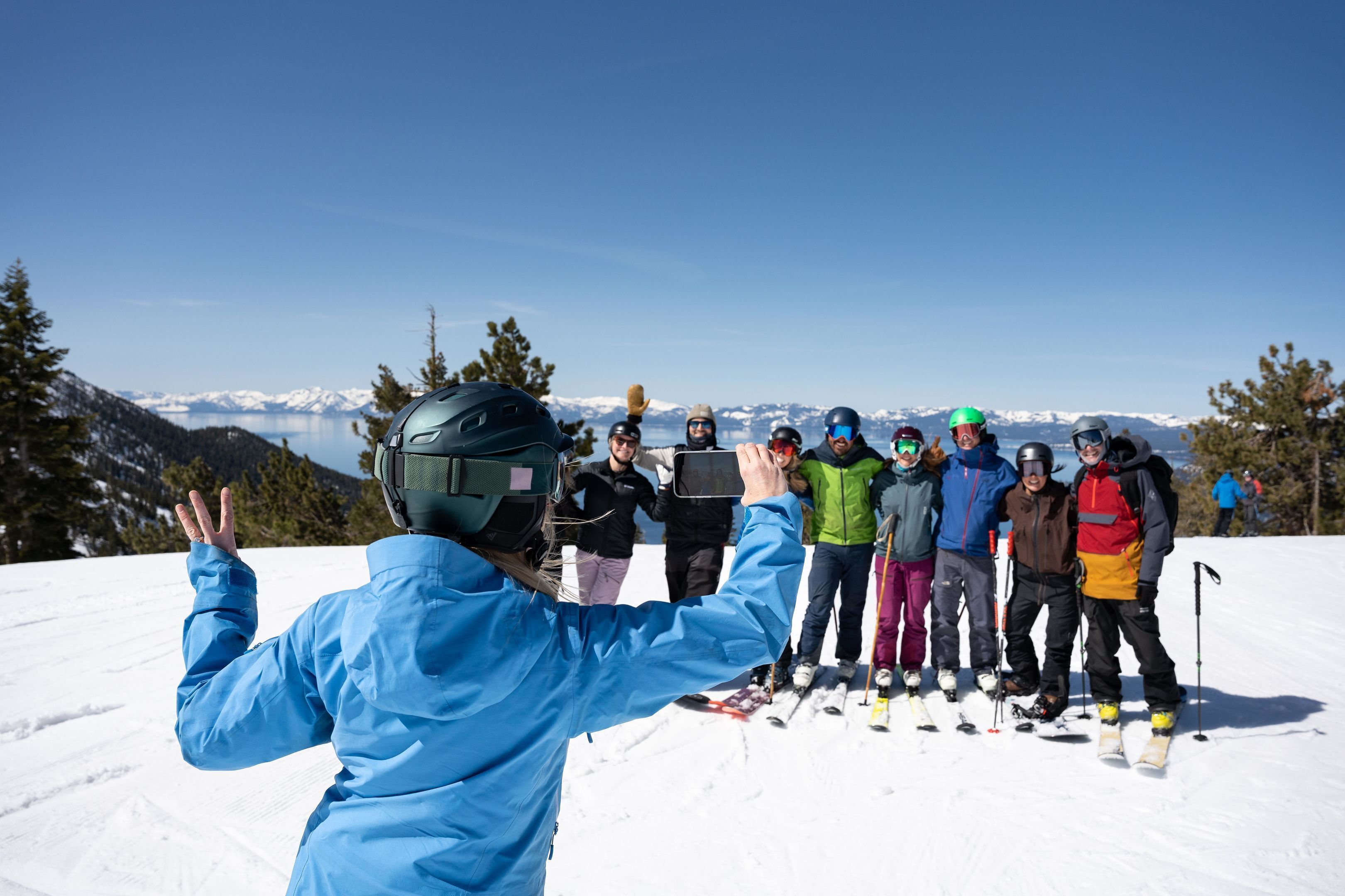 A group of people on a snowy mountain with a clear sky and distant mountains.