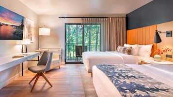 A modern hotel room with a large bed, a desk with a chair, a view of the outdoors through a sliding door, and a painting on the wall.