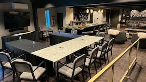 A modern conference room with a long table, chairs, and a bar area with seating.